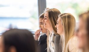 Group of students smiling while attending a presentation