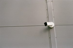 A CCTV camera pointing to the left, set on a stark, grey wall
