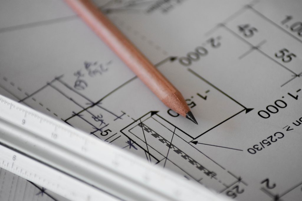 A pencil laid on top of some partially unrolled building plan diagrams