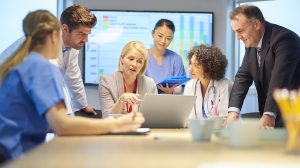 a mixed group of healthcare professional and business people meet around a conference table