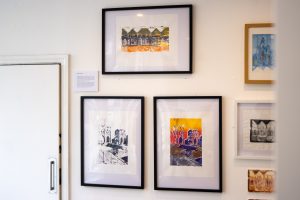 A wall display of framed prints of architectural buildings. Three large prints are arranged together, with two small prints beneath and additional framed artworks on the right.