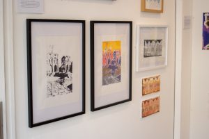 A gallery wall featuring framed prints of architectural scenes. Two large prints in black frames sit side by side, with smaller framed artworks arranged around them in various colours.